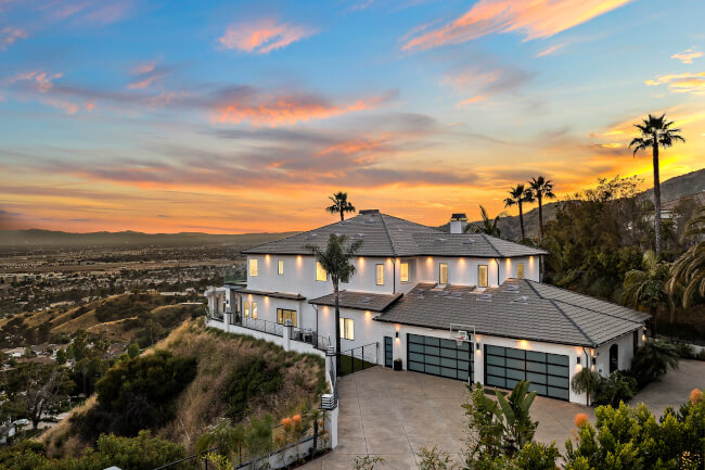 Luxurious hillside mansion with panoramic views and stunning sunset backdrop