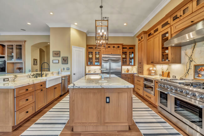Charming kitchen with marble countertops, high-end appliances, and warm wooden cabinetry